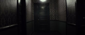 Movie still from “The Lords of Salem” (2012), directed by Rob Zombie – A dark room with a light shining on the door; Wide shot, Overhead angle