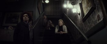 Movie still from “The Lords of Salem” (2012), directed by Rob Zombie – A woman sitting on top of a set of stairs next to another woman; Wide shot, Low angle