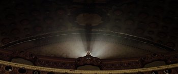 Movie still from “The Lords of Salem” (2012), directed by Rob Zombie – A person is sitting on a stage in a theater; Extreme Wide shot, Low angle