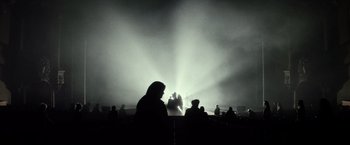 Movie still from “The Lords of Salem” (2012), directed by Rob Zombie – A group of people standing in front of a stage with lights; Extreme Wide shot, Low angle
