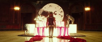 Movie still from “The Lords of Salem” (2012), directed by Rob Zombie – A person in a costume sitting in front of an image of marilyn monroe; Wide shot, Low angle