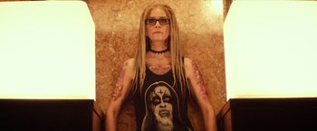 Movie still from “The Lords of Salem” (2012), directed by Rob Zombie – A woman with dreads and tattoos sitting on a wall; Medium shot, Overhead angle
