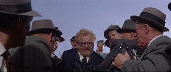 Movie still from “The Lost World” (1960), directed by Irwin Allen – A group of men standing next to each other in a field; Medium shot, Low angle