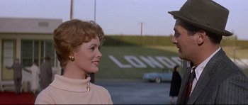 Movie still from “The Lost World” (1960), directed by Irwin Allen – A woman and a man standing next to each other on a street; Medium shot, Over the shoulder angle