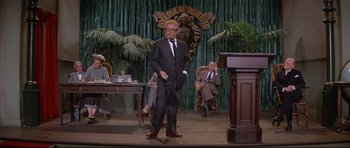 Movie still from “The Lost World” (1960), directed by Irwin Allen – A man in a suit and tie holding a sword; Wide shot, Over the shoulder angle