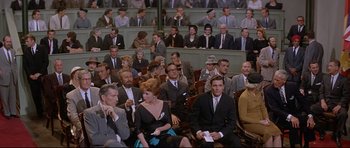 Movie still from “The Lost World” (1960), directed by Irwin Allen – A group of people sitting in a room; Wide shot, High angle