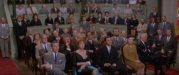 Movie still from “The Lost World” (1960), directed by Irwin Allen – A group of people sitting in chairs in a room; Wide shot, High angle