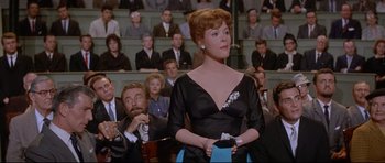 Movie still from “The Lost World” (1960), directed by Irwin Allen – A woman in a black dress is holding a wii controller; Medium shot, Low angle