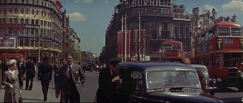 Movie still from “The Lost World” (1960), directed by Irwin Allen – A man standing next to a car on a street; Extreme Wide shot, Low angle