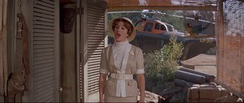 Movie still from “The Lost World” (1960), directed by Irwin Allen – A woman wearing a hat standing in front of an airplane; Medium shot, Low angle