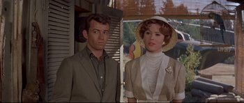Movie still from “The Lost World” (1960), directed by Irwin Allen – A man standing next to a woman wearing a hat; Medium shot, Low angle