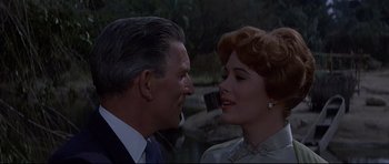 Movie still from “The Lost World” (1960), directed by Irwin Allen – An older man standing next to an older woman in front of a river; Close Up shot, Low angle