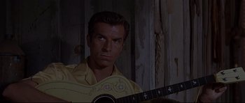 Movie still from “The Lost World” (1960), directed by Irwin Allen – A man holding a guitar in a room; Close Up shot, Low angle