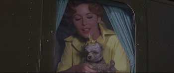 Movie still from “The Lost World” (1960), directed by Irwin Allen – A woman in a yellow shirt holding a small dog; Close Up shot, Low angle