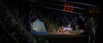 Movie still from “The Lost World” (1960), directed by Irwin Allen – A group of people sitting under a tent; Extreme Wide shot, High angle
