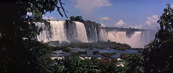 Movie still from “The Lost World” (1960), directed by Irwin Allen – A view of a large waterfall from across the river; Extreme Wide shot, Low angle