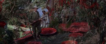 Movie still from “The Lost World” (1960), directed by Irwin Allen – A group of men standing next to a tree; Wide shot, High angle