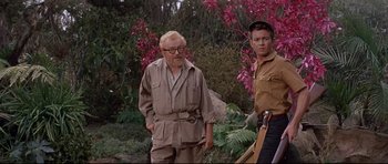 Movie still from “The Lost World” (1960), directed by Irwin Allen – A man and a boy standing next to each other in a field; Medium shot, Over the shoulder angle