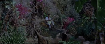 Movie still from “The Lost World” (1960), directed by Irwin Allen – A man sitting on top of a tree holding a guitar; Wide shot, High angle