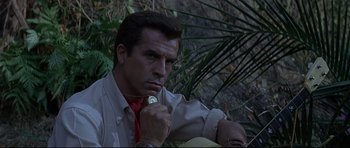 Movie still from “The Lost World” (1960), directed by Irwin Allen – A man in a red neck tie holding a coin; Close Up shot, Low angle