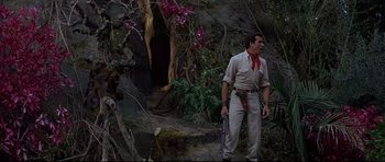 Movie still from “The Lost World” (1960), directed by Irwin Allen – A man standing in the woods holding a gun; Wide shot, Low angle