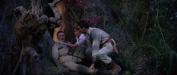 Movie still from “The Lost World” (1960), directed by Irwin Allen – A group of people sitting on the ground in the woods; Medium shot, Low angle