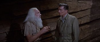 Movie still from “The Lost World” (1960), directed by Irwin Allen – A man and a man talking to each other; Medium shot, Over the shoulder angle