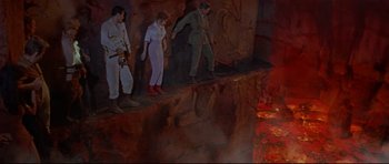 Movie still from “The Lost World” (1960), directed by Irwin Allen – A group of people standing next to each other on top of rocks; Wide shot, High angle