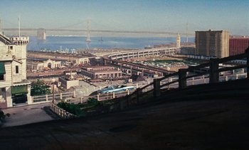Movie still from “The Love Bug” (1969), directed by Robert Stevenson – An aerial view of a city with a bridge in the background; Extreme Wide shot, High angle