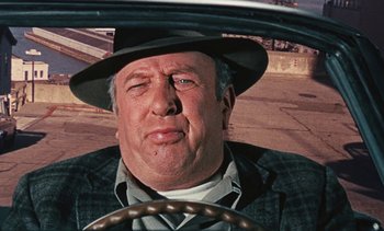 Movie still from “The Love Bug” (1969), directed by Robert Stevenson – An older man wearing a hat driving a car; Close Up shot, Over the shoulder angle