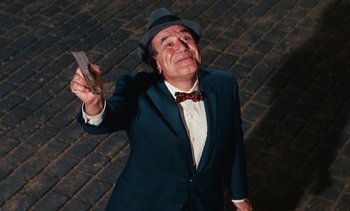 Movie still from “The Love Bug” (1969), directed by Robert Stevenson – An older man in a suit and hat holding a piece of paper in his hand; Medium shot, Low angle