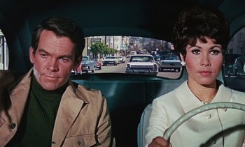 Movie still from “The Love Bug” (1969), directed by Robert Stevenson – A man and a woman sitting in the back of a car; Close Up shot, Over the shoulder angle