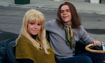 Movie still from “The Love Bug” (1969), directed by Robert Stevenson – A man and a woman sitting next to each other on the street; Medium shot, Low angle
