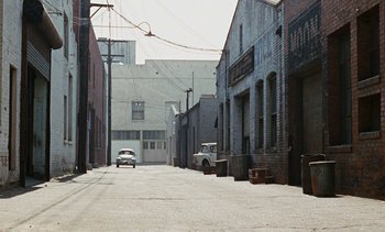 Movie still from “The Love Bug” (1969), directed by Robert Stevenson – An old car is driving down the street in an alley; Extreme Wide shot, High angle