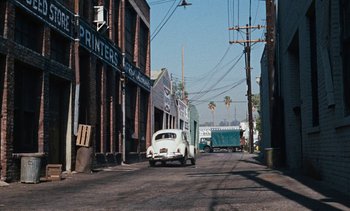 Movie still from “The Love Bug” (1969), directed by Robert Stevenson – An old car is driving down the street; Extreme Wide shot, High angle