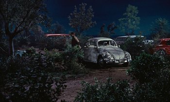 Movie still from “The Love Bug” (1969), directed by Robert Stevenson – An old vw beetle is parked in the dirt; Extreme Wide shot, High angle