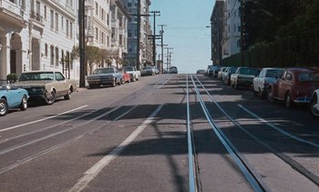 Movie still from “The Love Bug” (1969), directed by Robert Stevenson – Cars parked on the side of the road on a sunny day; Extreme Wide shot, High angle