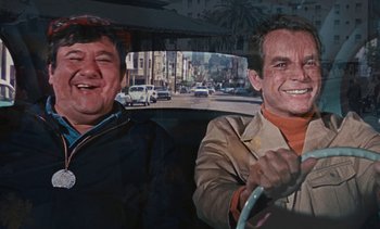 Movie still from “The Love Bug” (1969), directed by Robert Stevenson – Two men in the back seat of a car; Medium shot, Low angle
