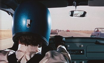 Movie still from “The Love Bug” (1969), directed by Robert Stevenson – A person wearing a blue helmet driving a car; Medium shot, Over the shoulder angle