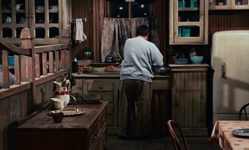 Movie still from “The Love Bug” (1969), directed by Robert Stevenson – A man standing in a kitchen preparing food; Wide shot, High angle