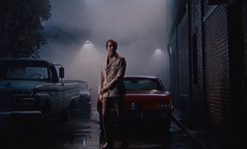 Movie still from “The Love Bug” (1969), directed by Robert Stevenson – A man standing next to a red car on the street; Wide shot, Low angle