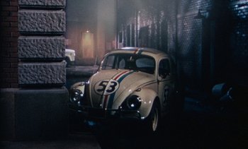 Movie still from “The Love Bug” (1969), directed by Robert Stevenson – An old vw beetle car is parked in front of a wall; Wide shot, High angle