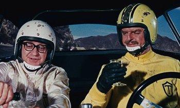 Movie still from “The Love Bug” (1969), directed by Robert Stevenson – A man and a woman sitting in the drivers seat of a car; Medium shot, Low angle