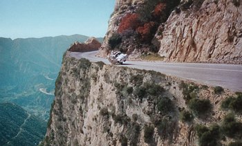 Movie still from “The Love Bug” (1969), directed by Robert Stevenson – A car driving on a mountain road with a cliff in the background; Extreme Wide shot, High angle