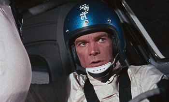 Movie still from “The Love Bug” (1969), directed by Robert Stevenson – A person wearing a helmet in a car; Close Up shot, Low angle