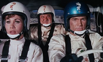 Movie still from “The Love Bug” (1969), directed by Robert Stevenson – A group of people in a car wearing helmets; Medium shot, Low angle