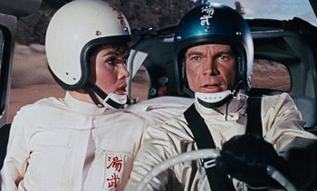 Movie still from “The Love Bug” (1969), directed by Robert Stevenson – A man and a woman wearing helmets in a race car; Close Up shot, Low angle