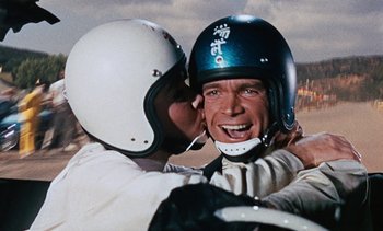 Movie still from “The Love Bug” (1969), directed by Robert Stevenson – A man wearing a helmet is hugging another man's face; Close Up shot, Over the shoulder angle