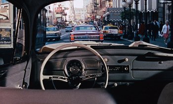 Movie still from “The Love Bug” (1969), directed by Robert Stevenson – A view from inside a car looking out the window at a busy city street; Wide shot, Over the shoulder angle