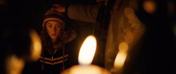 Movie still from “The Lovely Bones” (2009), directed by Peter Jackson – A woman standing next to a candle in a dark room; Close Up shot, Over the shoulder angle